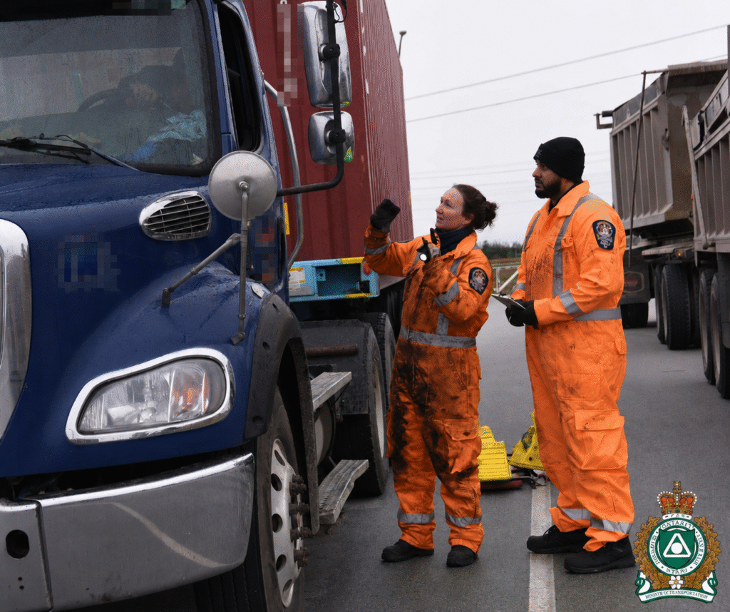 Two inspectors examining a commercial truck during a roadside brake inspection