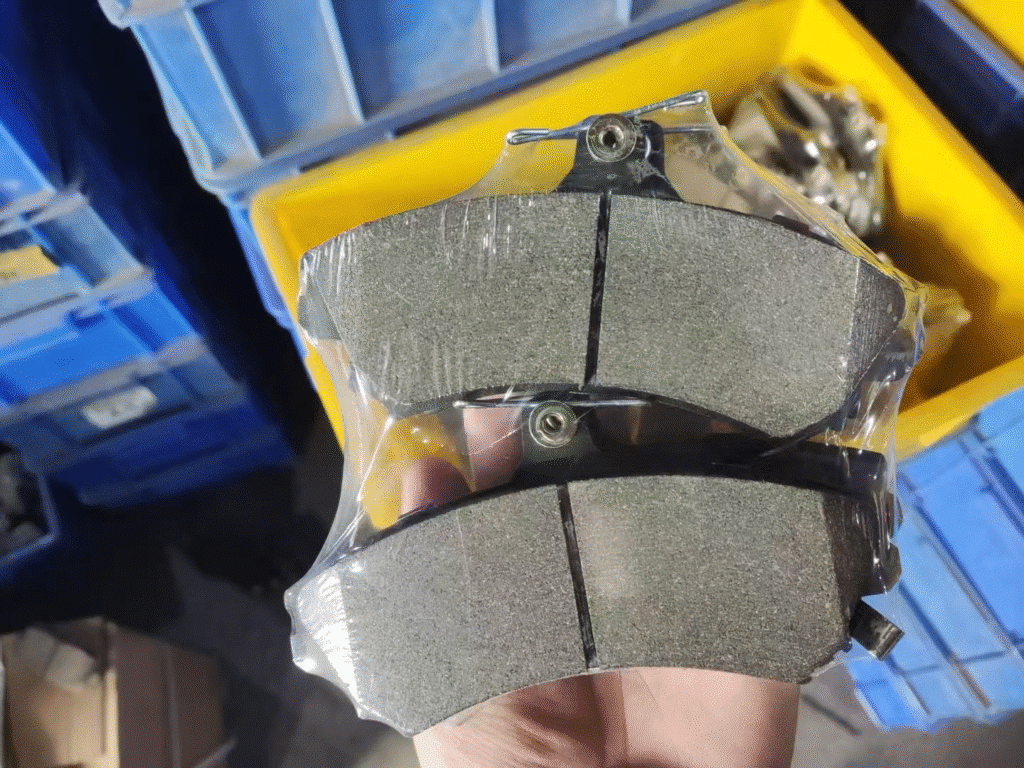 Two packaged commercial vehicle brake pads held for friction surface and backing plate inspection