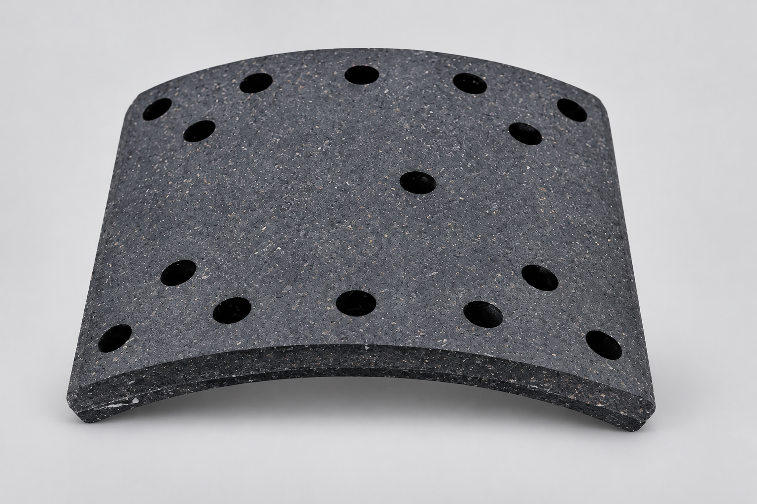 Heavy-duty curved drum brake lining showing its friction surface and rivet-hole pattern on a white background